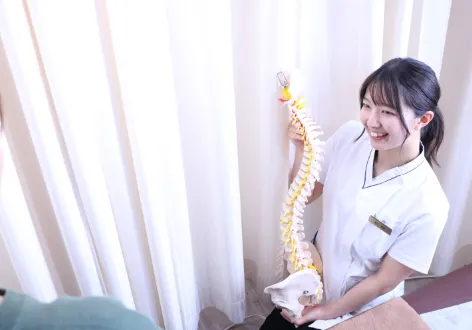 骨模型を使って説明する女性整体師