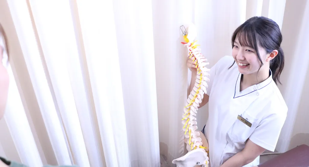 骨模型を持って説明する女性整体師